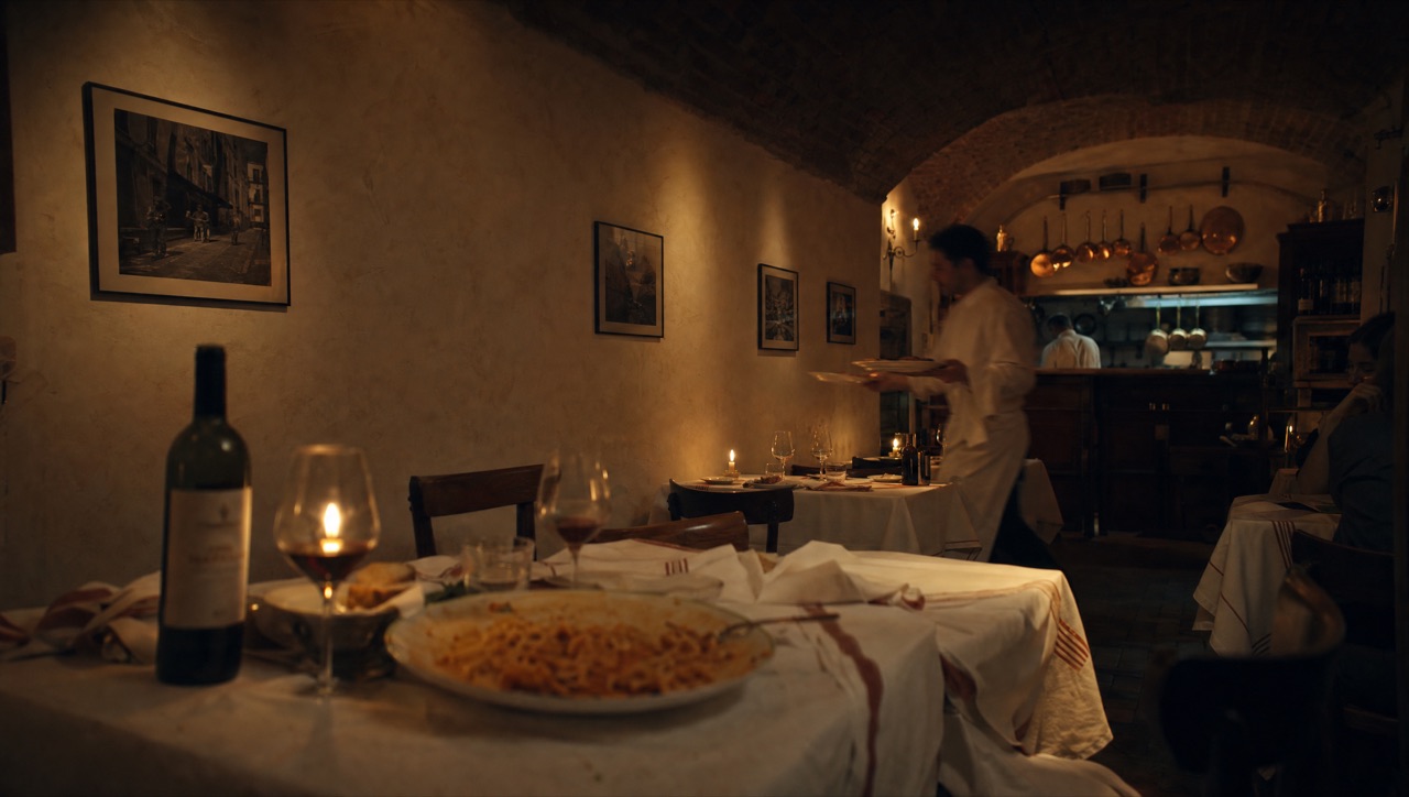 The candlelit interior of Nonna's — travertine walls, copper pans, white linen, dim and intimate