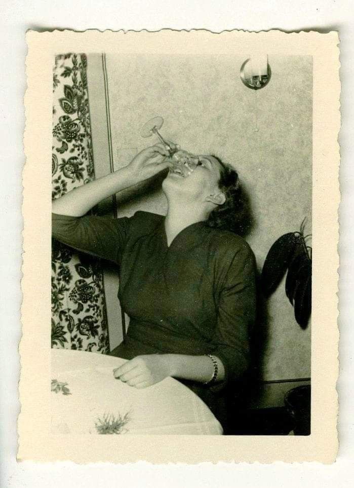 A woman tipping a glass back with a laugh, an old family photograph